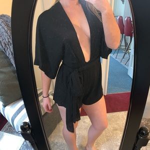 Black romper with a plunging neck line and versatile belt.